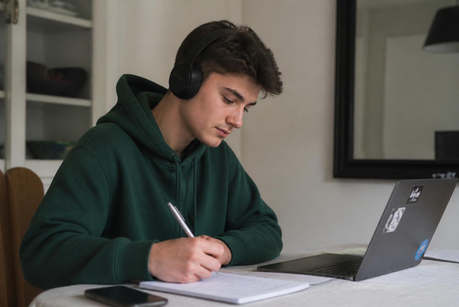 Étudiant suivant un cours du E-Campus SENZA sur son ordinateur portable, casque sur les oreilles